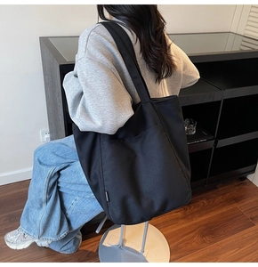 Side view of large black nylon tote bag showing the fashion label and spacious design