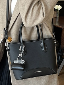 Classic black bucket tote bag with white lettering and a matching mini charm accessory