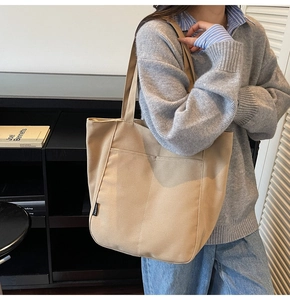 Detail shot of khaki nylon tote bag featuring dual front pockets and small fashion label
