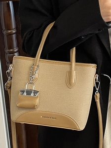 Fashionable beige bucket bag with brown leather trim and mini charm for women