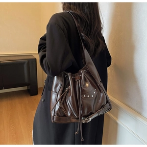 Detail view of deep brown oily leather bucket bag with silver rivets and studs