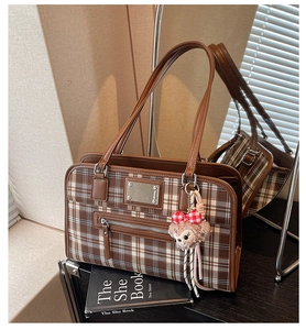 Detail of vintage plaid tote bag featuring leather patchwork and cute bear pendant charm