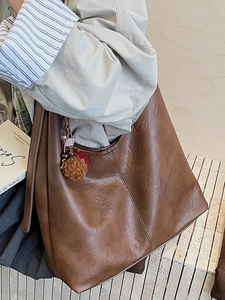 Large caramel brown leather bucket bag with plush charm accessory and side stitching