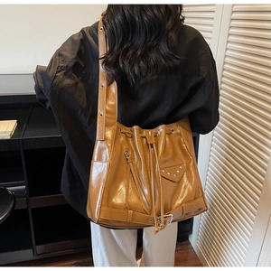 Detail view of brown glossy bucket bag featuring silver rivets and zipper accents