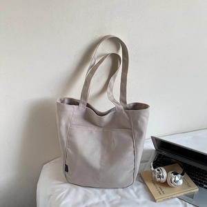 Detailed close-up of beige waterproof nylon tote bag with front pocket and laptop prop
