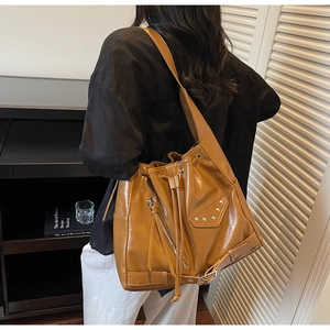 Detail view of brown vintage bucket bag with silver metal studs and zipper accents