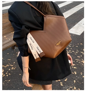 Detail of dark brown tote bag featuring V-shaped opening and textured wave pattern