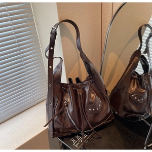Detail of dark brown oil wax leather bucket bag with silver studs and tassel zipper