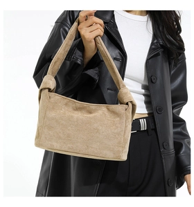 Détail du sac cabas en daim kaki avec poignées nouées porté par un mannequin de mode