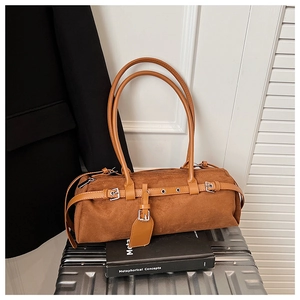 Detailed close-up of a caramel brown suede baguette bag with metal buckle and shoulder straps