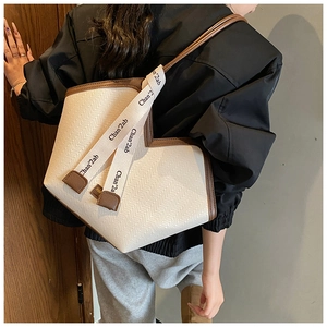 Detail of vintage beige woven tote bag with brown leather trim and branded logo shoulder strap