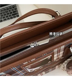 Close-up of smooth silver zipper and plaid pattern texture on brown commute tote bag