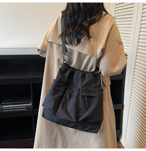 Detail view of large black nylon tote bag with functional pockets and adjustable strap