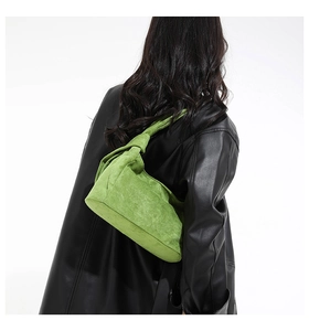 Détail du sac à bandoulière en daim vert avec bandoulière nouée porté par un mannequin
