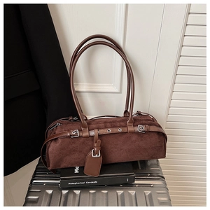 Detail of dark brown suede shoulder bag with metal eyelets on a silver suitcase