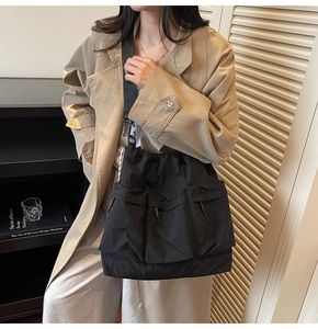 Detailed view of black multi-pocket nylon crossbody bag with drawstring on model