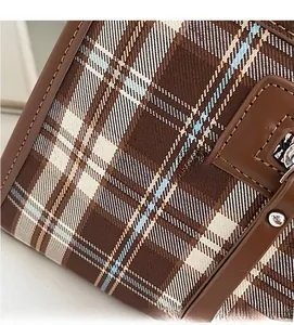 Detailed macro view of the brown plaid fabric and leather strap on the tote bag