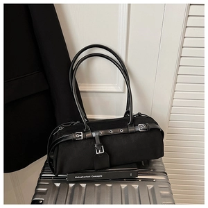 Detail of black suede bowling bag featuring silver buckles and leather strap on a suitcase