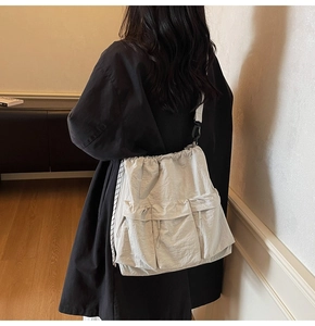 Detail of grey slouchy drawstring tote bag with dual front pockets and glossy texture