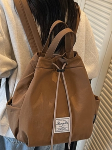Brown minimalist drawstring backpack with travel label shown from back on a model