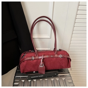 Close-up of a burgundy suede baguette bag with silver buckles and dual long handles