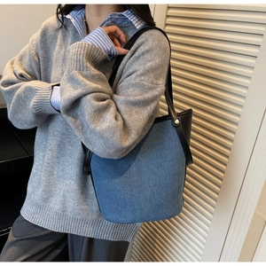 Detail of blue denim tote bag with black leather straps and silver rivet accents