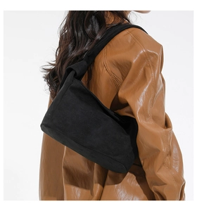 Détail du sac à bandoulière en daim noir avec design de sangle nouée et texture douce et élégante
