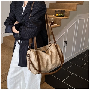 Detailed view of beige canvas Boston bag with leather straps and metal hooks on stairs