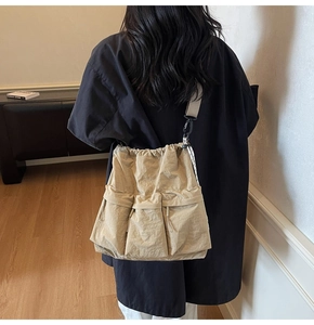 Rear view of a model wearing the khaki multi-pocket nylon crossbody bag with drawstring closure