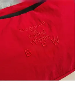 Close-up of red nylon canvas bag with tonal embroidery and black trim detail