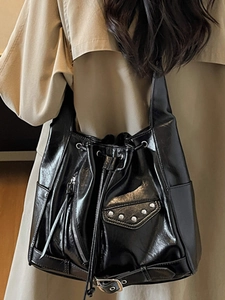 Retro black bucket bag with silver studs and high-gloss oil finish shown on shoulder