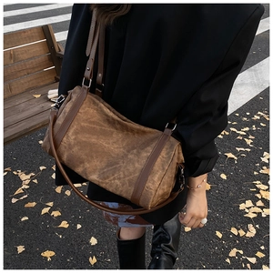 Vintage brown cylindrical shoulder bag shown in an autumn street setting with fallen leaves