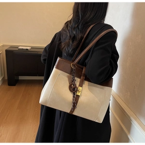 Détail du sac cabas bicolore avec fermoir métallique et pendentif tressé sur modèle