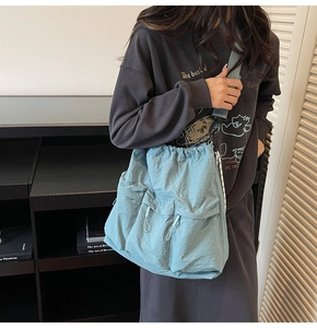 Detail of light blue nylon crossbody bag with drawstring pockets and workwear utility style