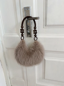 Dettaglio borsa in ecopelliccia con manico in corda intrecciata e perle di legno scuro