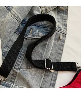 Detail view of the adjustable wide black fabric strap with silver metal buckles on a bag