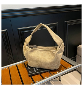Détail d'un sac à main en daim kaki avec poignée à nœud torsadé sur un banc en bois rétro