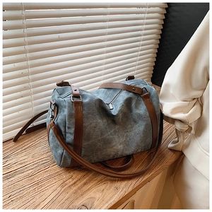 Close-up of vintage blue denim Boston bag with brown faux leather handles and strap