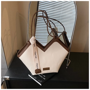Detail of V-shaped woven tote bag with brown leather trim and decorative ribbon strap