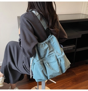 Detail of blue drawstring shoulder bag with crinkled nylon fabric and adjustable strap