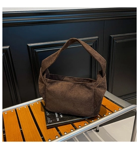 Détail d'un sac à bandoulière en daim marron foncé au design rétro sur une chaise