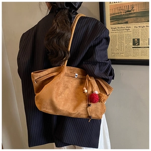 Détail du sac cabas en daim caramel avec pompons bohèmes et fines bandoulières