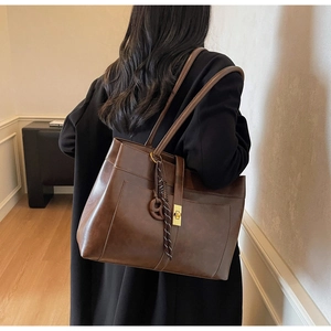 Détail du sac cabas en cuir marron foncé avec boucle métallique vintage et décoration pompon