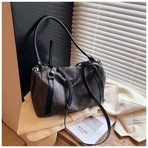 Detailed view of dark grey canvas Boston bag on beige jacket with natural light and shadows