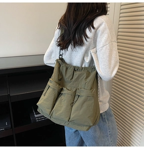 Detail of army green nylon crossbody bag with multi-pocket design and drawstring closure