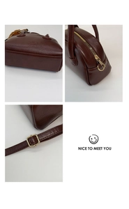 Detail view of dark brown textured leather bag showing bottom logo and gold zippers