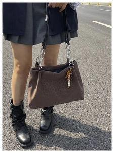 Detail of dark brown leopard suede tote bag with thick silver chain and beaded charm