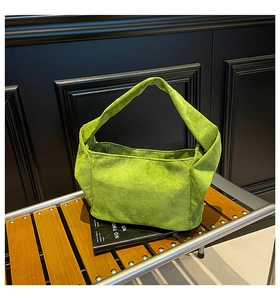 Détail du grand sac cabas en daim vert citron avec large poignée sur un banc chic