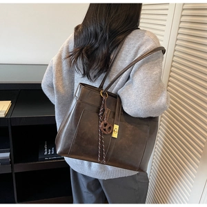 Détail d'un sac cabas marron foncé en cuir vintage avec un fermoir rotatif doré carré