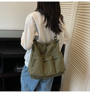 Detail showing army green nylon utility bag with three front pockets and drawstring